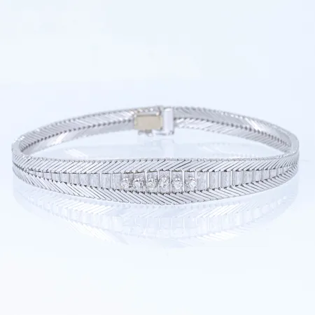 Armband i 18K vitguld: Halvstelt med 6 x c:a 0,02ct briljantslipade diamanter. Det är 5,8 - 10,6 mm brett, 20 cm långt och väger 25,4g. Kistlås. 