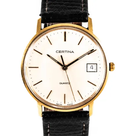Herrur Certina i 18K med svart läderband. Quartz. Boett Ø 33,5 mm. Gravyr "Umeå Kommuns Hedersgåva". Repigt plastglas. Går ej - Batteribyte krävs?