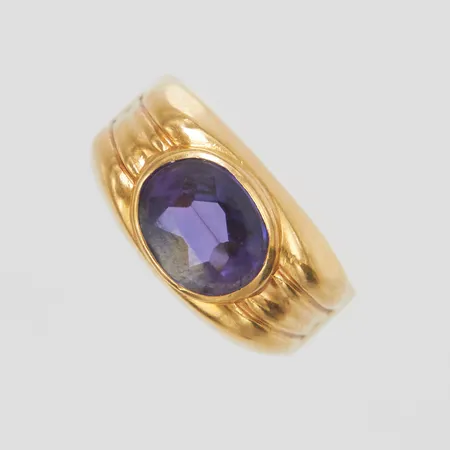 Ring med en färgväxlande syntetisk safir, Ø17¼, bredd: 3,8-9,2mm, svenska stämplar, något skev ringskena, 18K Vikt: 3,5 g