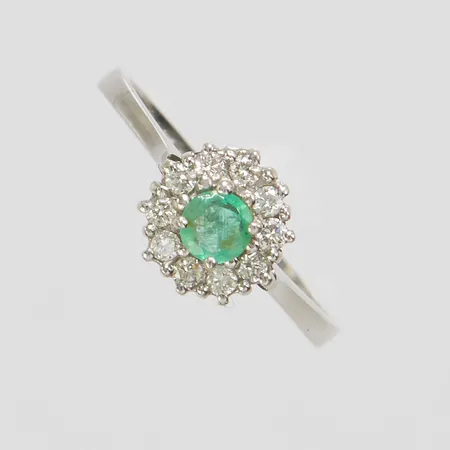 Karmoséring med en smaragd Ø ca.4mm samt diamanter 10 x ca.0,015ct, Ø17½, bredd: 1,9-8,4mm, vitguld, litet hack på insidan av skenan, 18K Vikt: 2,8 g