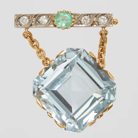Brosch i platina och 18K med en smaragd ca.5x4,5mm samt gammalslipade diamanter 4 x ca.0,05ct, 26,8x3,8mm, sannolikt omarbetad med en blå syntetisk spinell i kedja 18K, bruttovikt 13,9g.