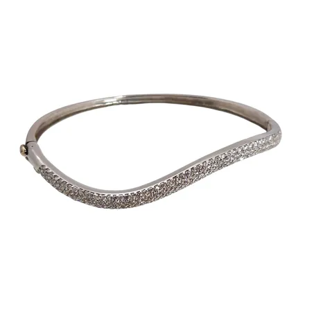 Armring, 18K vitguld, svängd modell, oval form, öppningsbar, vita stenar, ostämplad, inre omkrets 17 cm, bredd 3 - 4,5 mm, några små ojämnheter i skenan Vikt: 11,9 g