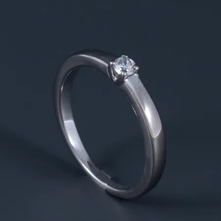 Ring i 18K vitt guld med 1 x 0,10ct briljantslipad diamant (ca W/si) i en låg fyrklofattning. Den är 1,7 - 3,1 mm bred, är i storlek 17½ och väger 3,7g. Stenstorleken stämplad i ringen. Stämplad GHA (Guldfynd) & 750.