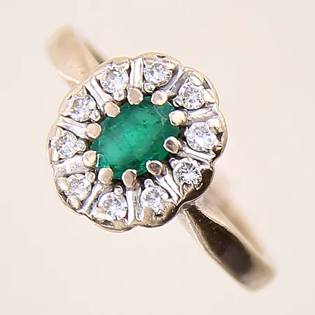 Carmoséring med briljantslipade diamanter 10xca0,02ct samt troligen grön smaragd, stl: 16, bredd: 2-11,1mm, ojämn skena, behov av omrodiering, vitguld, sliten sten, gravyr, 18K Vikt: 3,9 g