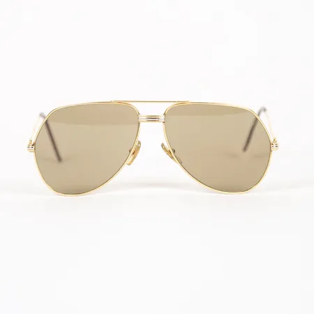 Solglasögon, Cartier, "Tank Louis", år 1983, pilotmodell med gulbruntonade glas, modellnr: 62-14-140, 22K guldpätterad metall, mindre repor på glas, mindre skeva, originalbox märkt must de Cartier Paris. Liknande solglasögon kan ses i filmen James Bond - "A view to a kill" (Levande Måltavla) från 1985, där liknande glasögon bärs av skurken Max Zorin, spelad av Christopher Walken Vikt: 0 g
