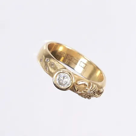 Ring med diamanter 1x 0,44ct, 6x 0,005ct enl. gravyr, dekor av skorpion, stl 19½, bredd 5-6mm, tillv. Guldsmedsmästarn i Göteborg år 2000, svar personlig gravyr, 18K Vikt: 9 g