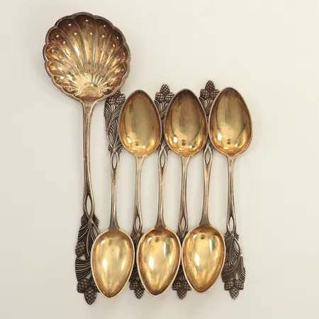 Sex kaffeskedar, längd 11,5cm, en sockerströare, längd 16cm, dekor av kottar och blad, delvis förgyllda, finska stämplar, silver  Vikt: 91,6 g