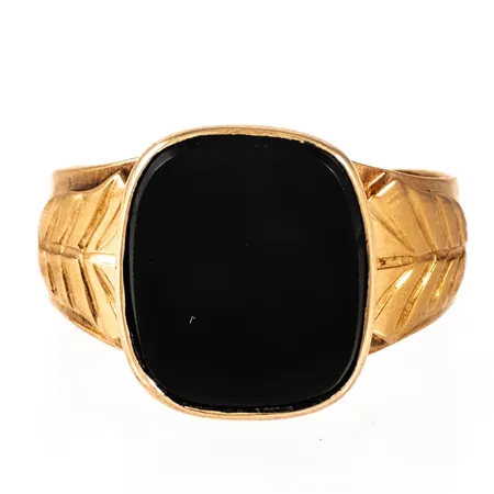Klackring i 18K guld med svart sten (troligen onyx eller svart agat). Den är 3,9 - 14,3 mm bred, är i storlek 19 och väger 6,4g inklusive sten. Stämplad K9 (1960), KLD (Lund Ur & Guldsmedsaffär, Örnsköldsvik), 18K & Kattfot.