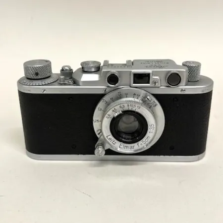 Kamerahus Leica II, serienr 200626, år 1936, objektiv Leitz Elmar f=5cm 1:3,5, serienr 291987, buckla undertill, lätt slitage på metallen, motljusskydd Elmar 5cm Ernst Leitz Wetzlar, nyutgåva Leica-katalog 1936. Ej funktionstestad. 