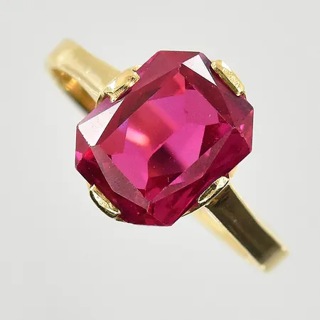 Ring med röd sten, stl 17¼, bredd 2-11 mm, ostämplad, 18K. Vikt: 2,6 g