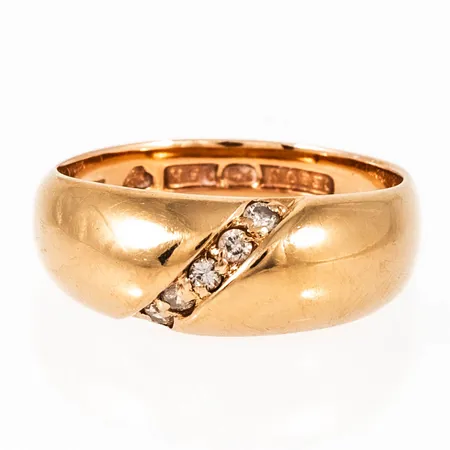 Ring i 18K guld med 5 x 0,02ct briljantslipade diamanter. Den är 3,5 - 7 mm bred, är i storlek 16¾ och väger 4,5g. Stämplad CESON (Ceson Guldvaru AB, Göteborg), B10 (1976), 18K & Kattfot. Caratvikt ingraverad i ring.