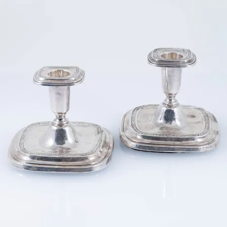 Ett par ljusstakar, höjd ca 8 cm, fyllda bottnar (lös från en av stakarna). Bucklor, gravyr och ojämnheter. Stämplad CGH (C G Hallbergs Guldsmeds AB, Stockholm), F9 (1956), Silverstämpel & Kattfot. Bruttovikt: 371,4g. 