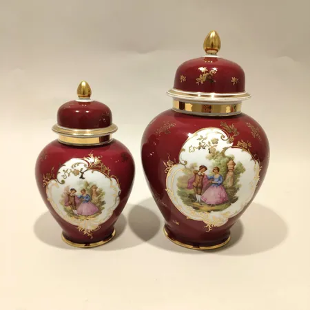  Två lockurnor Trianon, romantisk dekor mot röd botten, ca 16,5cm, 21,5cm, porslin Skickas med paket.