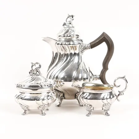 Kaffeservis, tre delar, rokokostil, kaffekanna med svarvat trähandtag, gräddkanna samt sockerskål med invändig förgyllning, C. G. Hallbergs Guldsmedsaktiebolag, Stockholm är 1946, höjd: 8 - 21 cm, gravyr på undersidan, mindre buckla på kaffekanna, silver. Bruttovikt: 692,6g Vikt: 0 g