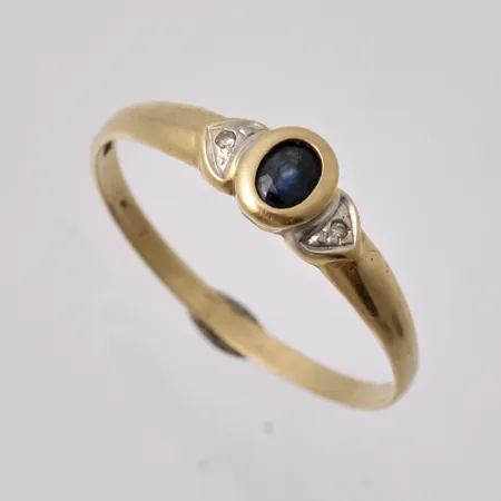 Ring i 18K guld, stl 19, bredd 1,76-5,7mm, 1st blå sten, mått 3,2x4mm, 2st vita stenar, vikt 1,58g.