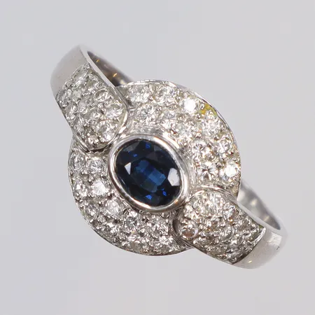 Ring med diamanter 46x ca 0,015ct (totalt 0,75ctv enl. gravyr) och blå sten (safir 0,61ct enl. gravyr), stl 20½, art-deco stil, bredd 2-13mm, importstämplad av Heribert Engelbert, vitguld 18K Vikt: 4,4 g