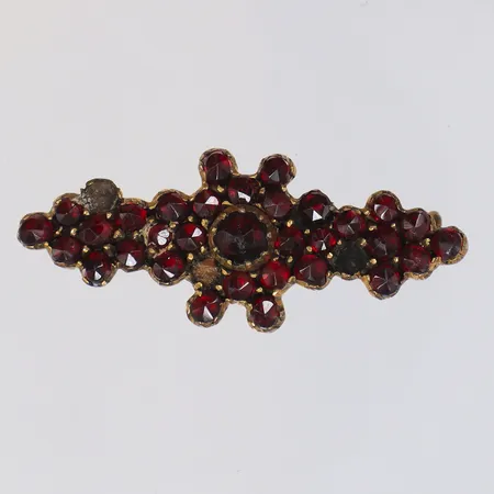 Brosch i gulmetall med röda stenar, troligen granater, saknar tre stenar, 38x14mm, graverad och daterad baksida år 1901