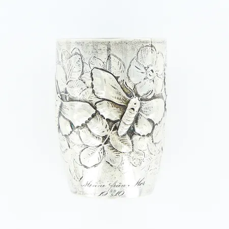 Mugg med dekor av blommor, blad och fjärilar i relief, gravyr, EM.O. Möller, Malmö 1907, höjd 8,5cm, Ø6cm, silver 830/1000. Vikt: 100,3 g