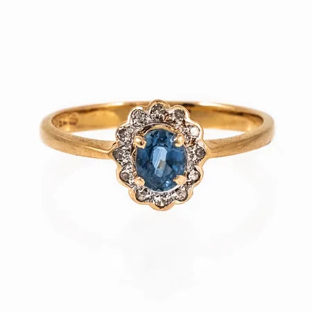 Carmoséring i 18K guld med ljusblå sten och 12 x c:a 0,005ct åttkantslipade diamanter. Den är 2,2 - 8,8 mm bred, är i storlek 17¼ och väger 2,0g. NSE, 750 & Kattfot. Nagg på flera diamanter. 