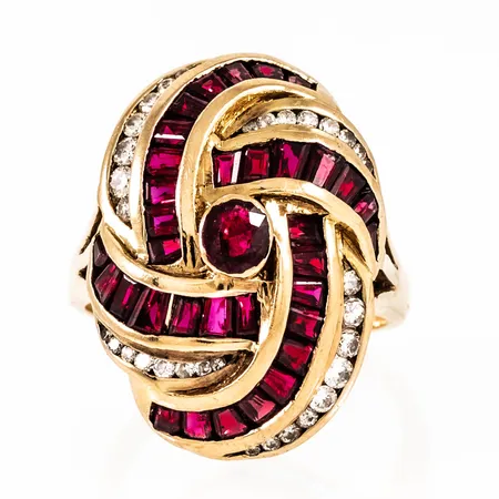 Ring i 18K guld med 35 rubiner, 34 briljantslipade diamanter totalt c:a 0,40ct. Den är 2,2 - 25,2 mm bred, är i storlek och väger 11,7g. Enstaka rubiner med nagg. De är knallröda "i verkligheten", men svåra att fota.