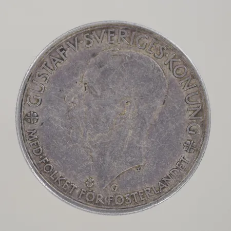 Mynt, "Gustaf V Sveriges Konung,  Med folket för fosterlandet,  Sveriges Riksdag 1435-1935, 5kr", silver 925/1000. En Silverbrosch fjäril  L 4cm H 3,5cm, 830/1000   Vikt: 31,5 g