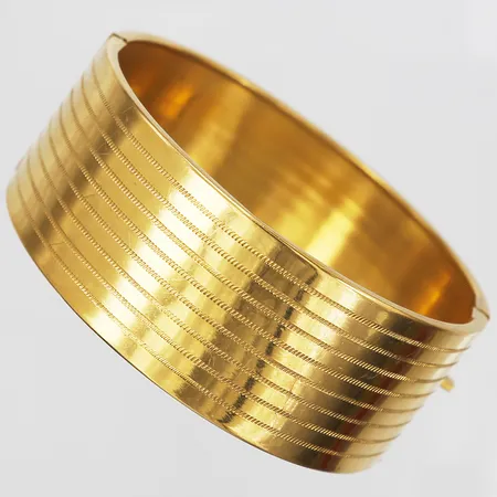 Armring med ciselerad randig dekor, innermått 60mm, bredd 23mm, kistlås med dubbla låsåttor, 22K guld Vikt: 34,3 g