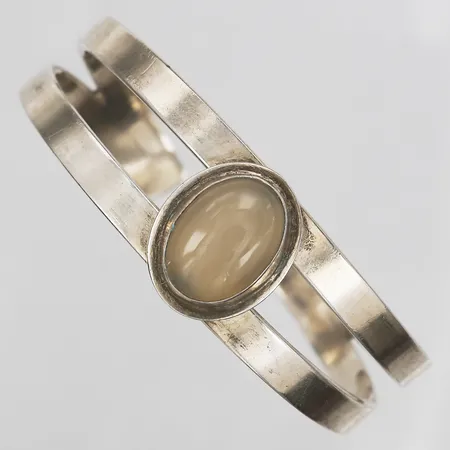 Armring med cabochonslipad vit sten, signerad EH, Gävle, 1961, innermått ca Ø66x60mm, bredd 18-22mm, slitage, skevt, 925/1000 silver. Vikt: 46,3 g