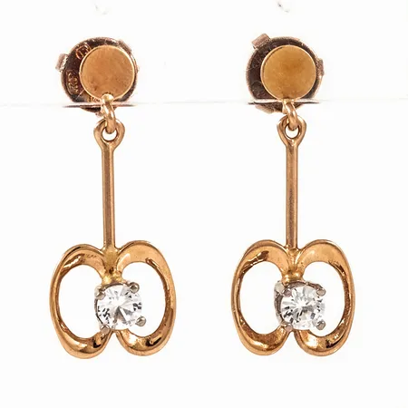 Hängande örhängen i 18K guld med vita stenar. De är 23 mm långa, 4 - 9,2 mm breda och väger 2,1g.