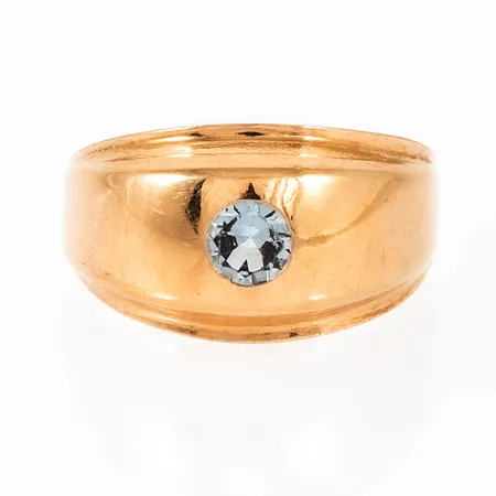 Doserad ring i 18K guld med ljusblå sten fattad i lordfattning. Den är 3 - 10,5 mm bred, är i storlek 17 och väger 2,1g. Kattfot. Något ojämn skena.