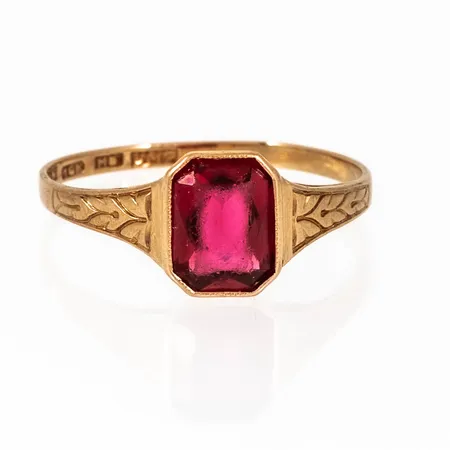 Ring i 18K guld med röd sten och mönsterdekor. Den är 1,4 - 8,4 mm bred, är i storlek 18½ och väger 1,6g. 18K & Svensk importstämpel. Repig, lös sten. 