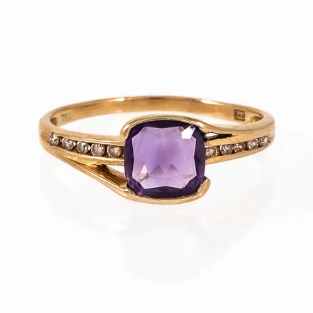 Ring i 18K guld med lila sten och 10 x c:a 0,01ct åttkantslipade diamanter. Den är 1,5 - 8 mm bred, är i storlek 19 och väger 2,8g. GHA, 750.