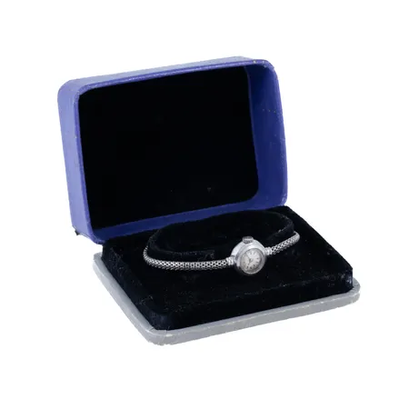 Defekt smyckeur Girard Perregaux i vitt guld 18K med integrerat band. Boett Ø 15,5 mm. Manuellt urverk. Repigt plastglas. Fuktskadad urtavla. Band med viklås. Ställbar längd 17,5 / 18 cm, 3,5 mm brett. Bruttovikt 14,0g. Originalask. Går ej!