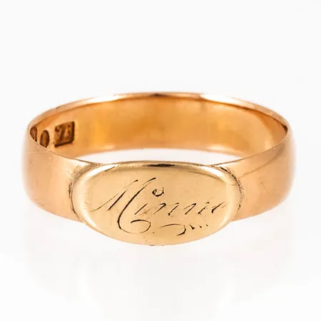 Ring i 18K guld. Platta med gravyr "Minne". Den är i storlek 19-, är 4,5 - 6,5 mm bred och väger 3,7g. Stämplad PAÖ (Per August Öhman, Lycksele), Y6 (1901), 18K & Kattfot.