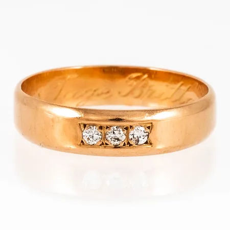 Ring i 18K guld med 3 x 0,02ct briljantslipade diamanter. Den är i storlek 19½, är 4,5 mm bred och väger 3,7g. Stämplad UGG (Guld & Gravyr, Umeå), 18K & Kattfot. Stenstorlek graverad. Gravyr.