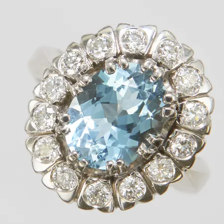 Karmoséring med en oval, briljantslipad akvamarin ca.9,85x7,75x5,30mm samt diamanter 14 x ca.0,04ct, Ø16¾, bredd: 4-17,5mm, akvamarinen har ett mindre nagg under ena klon, svenska stämplar, vitguld, 18K Vikt: 9,8 g