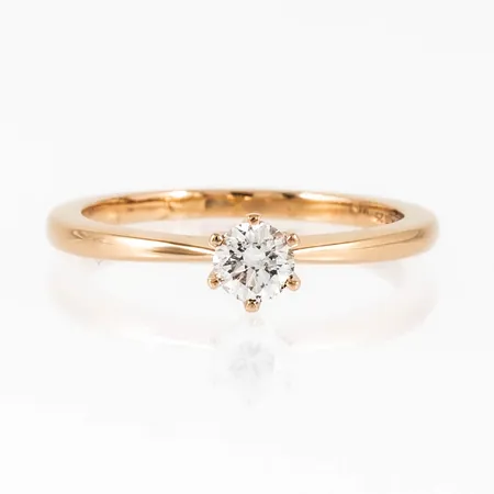 Ring i 18K guld med en briljantslipad diamant 0,25ct (W-si) i en låg sexklofattning. Den är 1,5 - 5 mm bred, är i storlek 16½ och väger 2,6g. Stämplad GHA (Guldfynd) & 750. Ingraverad stenstorlek och kvalitet. Fint skick. Nypris idag c:a 18.000kr.