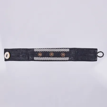 Armband i läder, Sameslöjd, med flätad tenndekor och blommor, knapp i horn, längd 18cm, bredd 25mm 