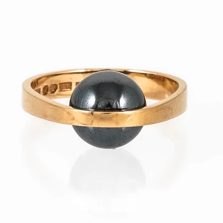 Ring i 18K guld med hematitkula. Den är i storlek 16¾, är 3,7 - 10 mm bred och väger 6,2g. Stämplad A11 (1999), ALTON, Falköping, 18K & Kattfot. 