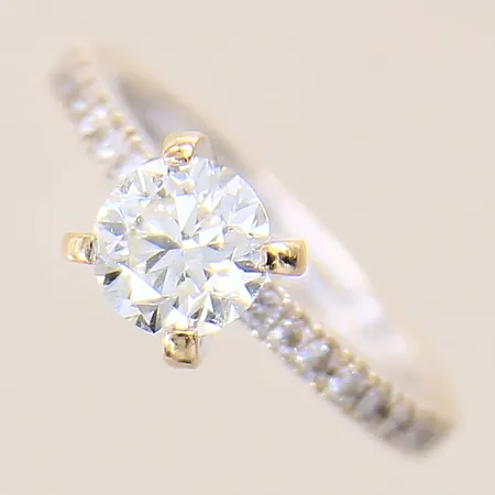 Ring med briljantslipade diamanter 1 x ca 0,80ct, kvalitet ca: Cr(J)/SI, fjäder som når ytan, samt 18 x ca 0,01ct, stl: 14¾, bredd: 1,9-5,9mm, vitguld/rödguld, 18K  Vikt: 3,2 g
