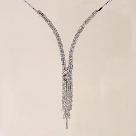 Collier med briljantslipade diamanter ca 120 x 0,01ct samt baguetteslipade 10 x ca 0,01ct, flertalet diamanter indikerar på att vara syntetiska, halvstelt, längd ca 39cm, bredd 1,5-3mm, vitguld, 18K  Vikt: 19,2 g
