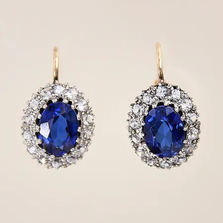 Ett par örhängen med syntetiska safirer samt vita stenar, 12x11mm, ena något skev vid stift, fattningsdel i silver, stift i 14K Vikt: 3,8 g
