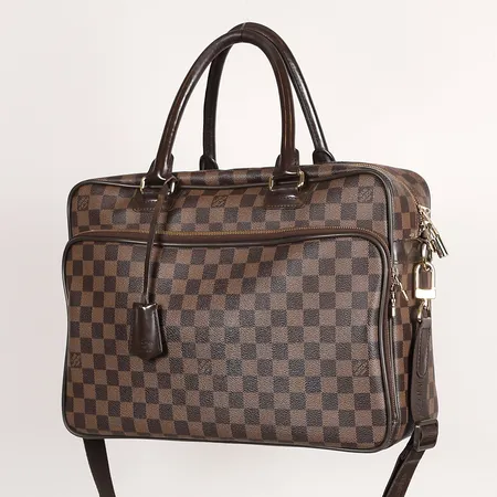 Väska/Datorväska, Louis Vuitton Icare Damier ebene canvas, brunt läder, mått ca 38x29x13,5cm, axelrem, läderhandtag, detaljer i guldfärgad metall, hänglås med tillhörande nycklar, invändigt klädd i tyg, samt innerfack, bruksslitage, handtag med slitage, skadad söm och foder vid dragkedja, mindre fläckar invändigt, kvitto från Affordable Luxury 2021. 
