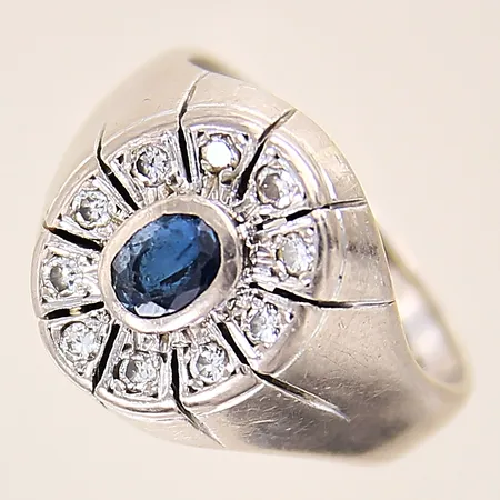 Ring med diamanter totalt 0,15ctv enligt gravyr samt safir 0,58ct enligt gravyr, stl 17¼, bredd 4-15mm, vitguld, safir med flertal mindre nagg på fasetter, i behov av omrodering, repig skena, gravyr, 18K  Vikt: 8,5 g