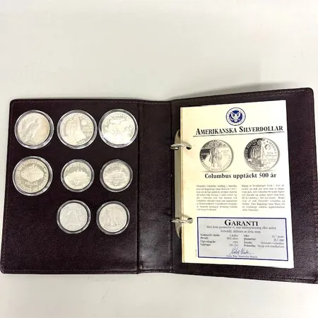 Myntsamling med åtta mynt, amerikanska silverdollar, Ø30,5-38mm, pärm med information, plastetuier, ett av mynten i silver 400/1000, resterande silver 900/1000  Vikt: 154,1 g