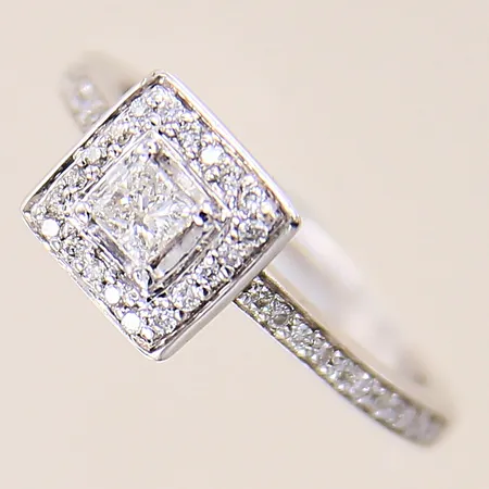 Ring med en princessslipad diamant ca 0,25ct samt briljantslipade diamanter ca 42 x 0,005ct, stl: 16¼, bredd: 1,6-7,9mm, vitguld, gravyr, 18K  Vikt: 3,2 g