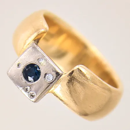 Ring med diamanter 1 x ca 0,01ct, 4 x ca 0,005ct samt troligen syntetisk blå safir, stl: 19½, bredd: 8mm, små repor vid skenan, nagg på sten, tvåfärgad, 18K  Vikt: 16,8 g