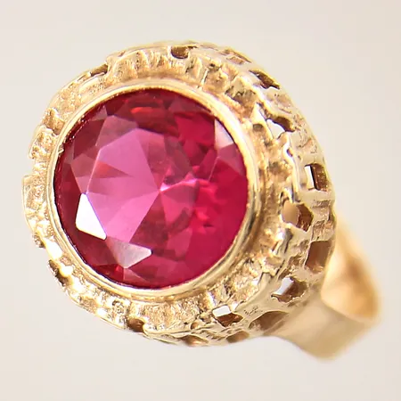 Ring med troligen syntetisk röd rubin, stl: 17¼, bredd: 3,9-14,1mm, litet nagg på sten, 14K  Vikt: 4,4 g
