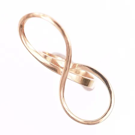 Ring med asymmetrisk form, längd 38mm, bredd 17mm, stl: 17¾, otydliga mästarstämplar, men troligen tillverkad av A Nilssons Guld AB, Nässjö 1977, 18K guld. Vikt: 6,1 g