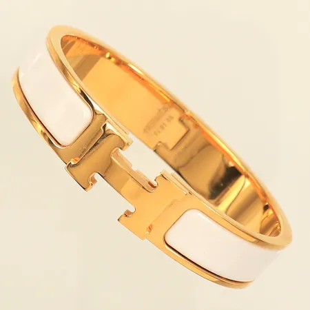 Armband Hermés Clic Clac H, guldfärgad metall med vit emalj, nr FI 01 55, mått ca 55x45mm, bredd 12mm, smärre repor, kvitto Kuala Lumpur daterat 22/02/2016, dustbag, etui. 