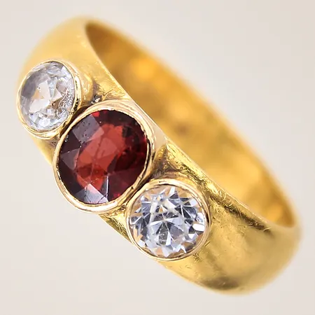 Ring med röd sten samt troligen syntetiska vita safirer, stl 17¾, bredd 5,5-6,5mm, skador på stenar, gravyr, fattat i 18K guld, skenan 23K.  Vikt: 8,2 g